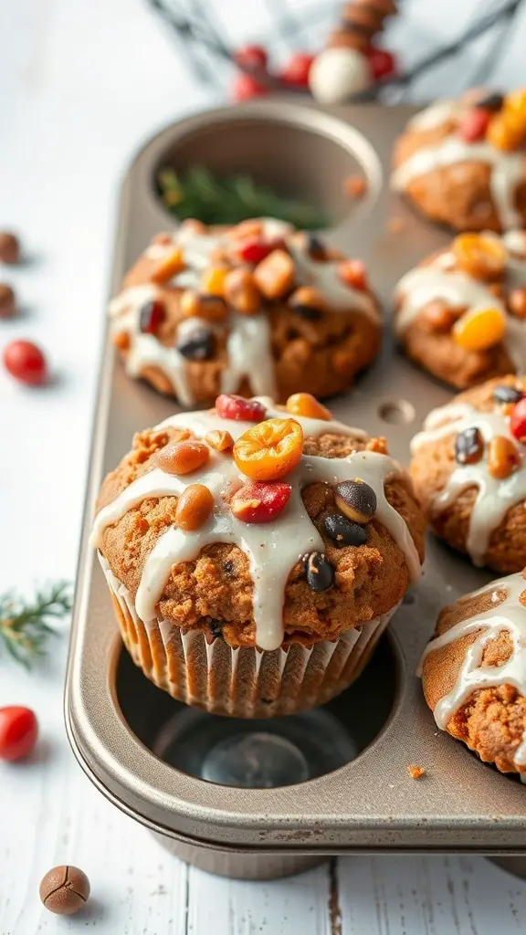 Fruitcake muffins with glaze in a muffin tin, topped with colorful fruits.